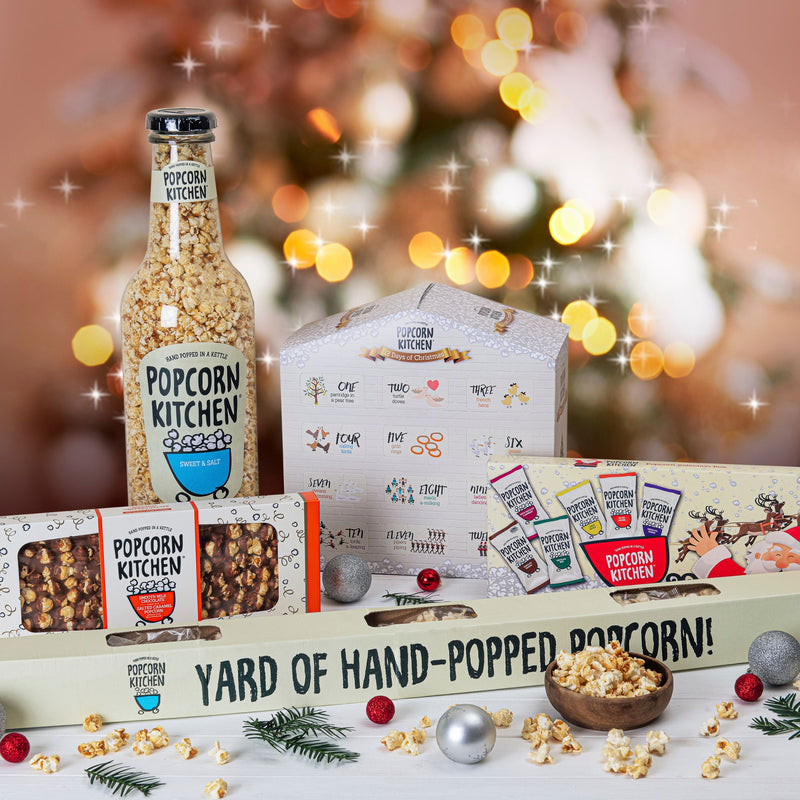 A selection of popcorn products including a giant bottle and an advent calendar with a Christmas background