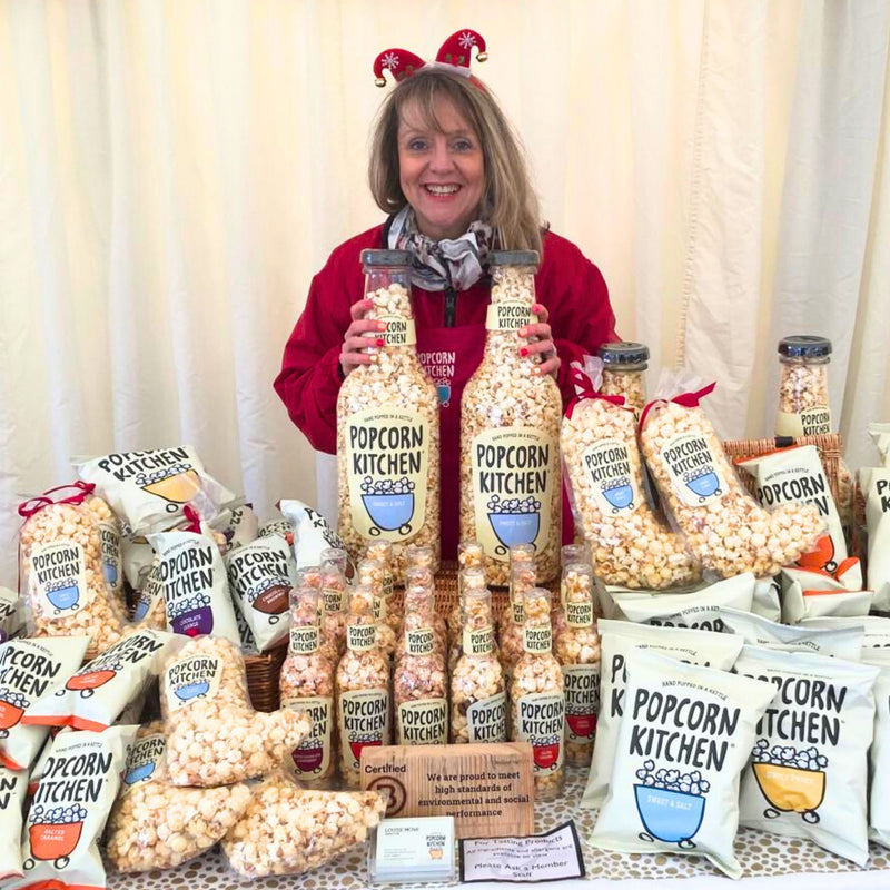 Louise at a tasting event with lots of popcorn products on a table