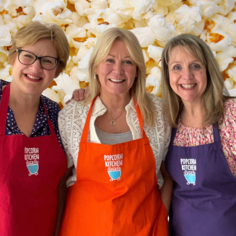 3 ladies with popcorn kitchen aprons