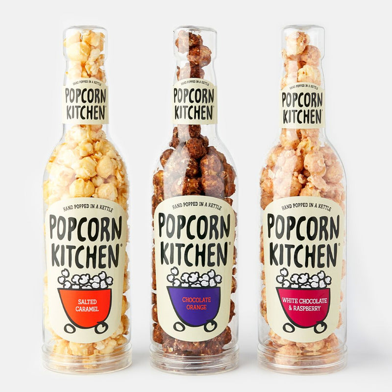 3 gift bottles of popcorn of flavours salted caramel, choclate orange and white chocolate and raspberry on a white background