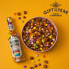 Pop At Home Rainbow Chocolate Bottle next to a bowl containing chocolate coated popcorn and rainbow chocolates. Gift of the year highly commended 2024 logo is showing