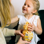 Girl with Easter Chick shaped container filled with popcorn with her mum