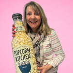 Woman holding lifesize version of popcorn bottle, flavour is sea salt