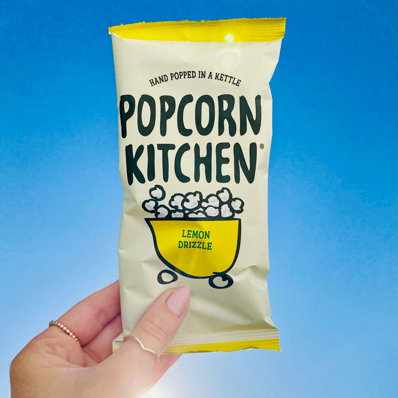 hand holding lemon drizzle popcorn snack bag